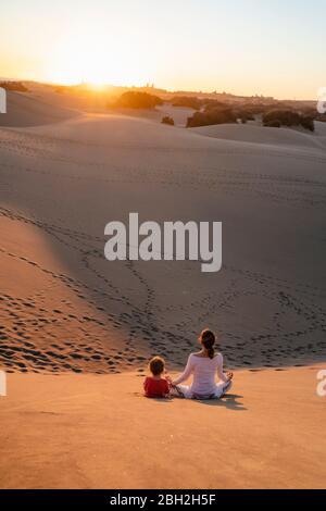 Madre e figlia si rilassano in dune di sabbia al tramonto, Gran Canaria, Spagna Foto Stock