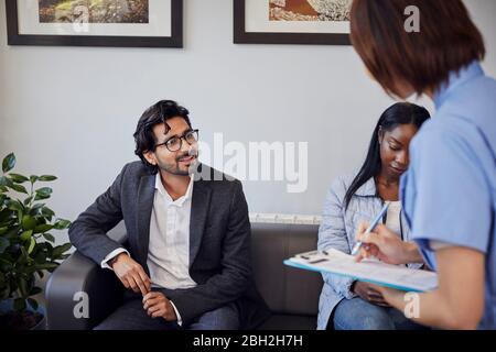 Receptionist che parla con il paziente in sala d'attesa di una pratica dentale Foto Stock