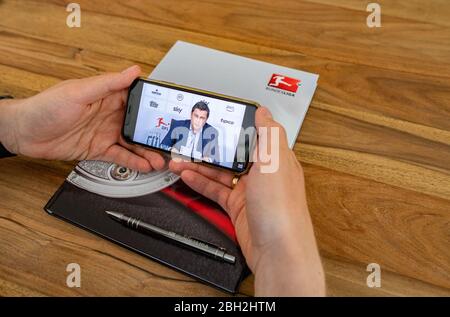 Warendorf, Germania. 23 aprile 2020. Un uomo guarda la mostra del suo smartphone, che mostra Christian Seifert, CEO e portavoce del Comitato Esecutivo della Lega di Calcio tedesca (DFL), durante una videoconferenza stampa dal vivo dopo l'incontro generale del DFL sulle conseguenze della pandemia di Corona. Credit: Guido Kirchner/dpa/Alamy Live News Foto Stock