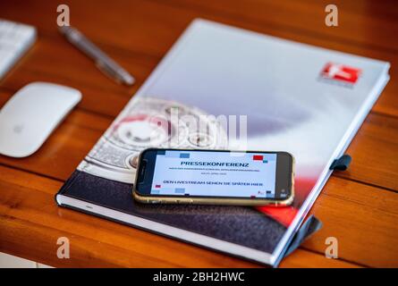 Warendorf, Germania. 23 aprile 2020. Un telefono cellulare sul cui display viene annunciata la conferenza stampa dal vivo dopo l'incontro generale DFL sulle conseguenze della pandemia di Corona è collocato su una scrivania. Credit: Guido Kirchner/dpa/Alamy Live News Foto Stock