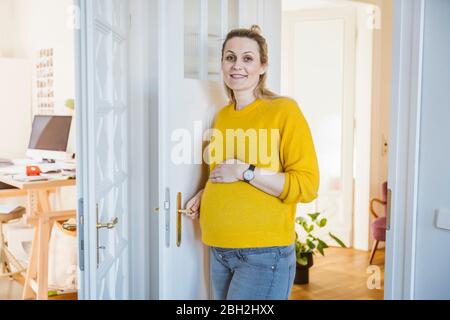 Ritratto di donna incinta sorridente a casa Foto Stock