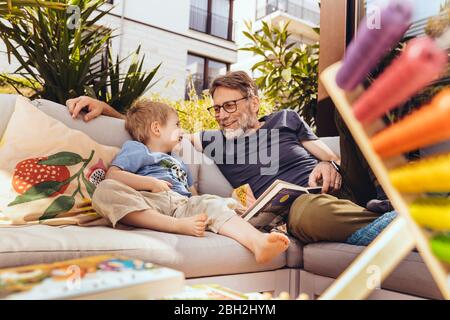 Padre e figlio che leggono un libro sulla loro terrazza Foto Stock