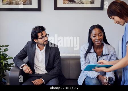 Receptionist che parla con il paziente in sala d'attesa di una pratica dentale Foto Stock