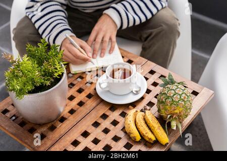 Primo piano di un uomo seduto al tavolo che prende appunti Foto Stock