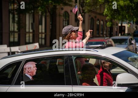 Richmond, Stati Uniti. 22 aprile 2020. Una donna fa ondare una piccola bandiera americana fuori dal tetto di una macchina con una foto di Donald Trump affissa alla sua finestra alla protesta 'riaprire Virginia' a Richmond il 22 aprile 2020. (Foto di Matthew Rodier/Sipa USA) Credit: Sipa USA/Alamy Live News Foto Stock