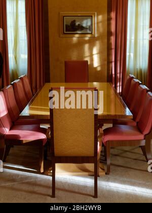 Bellissimo tavolo in legno Art Deco vintage e sedie rosse nella sala da pranzo, Eltham Palace, Londra, Regno Unito. Foto Stock