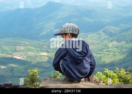 Ragazzi asiatici sedersi sulla roccia di vedere le montagne e il cielo di Phu Rua Parco Nazionale in Loei, Thailandia. Foto Stock