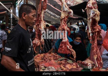 Lhokseumawe, Indonesia. 23 aprile 2020. Un commerciante che vende carne ai compratori durante la tradizione. La popolazione di Aceh ha ancora celebrato la tradizione "Meugang", anche se è stata vietata a causa delle preoccupazioni per l'epidemia di coronavirus COVID-19. L accoglienza del Santo mese di Ramadhan (Meugang) è una tradizione di Acehnese da centinaia di anni. Credit: SOPA Images Limited/Alamy Live News Foto Stock