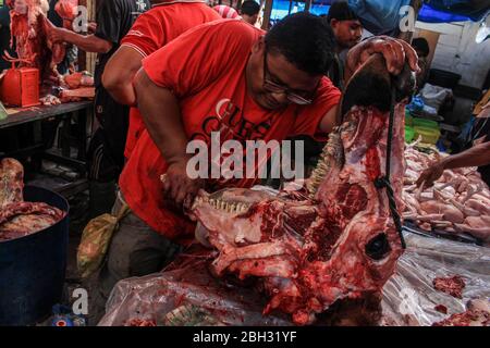 Lhokseumawe, Indonesia. 23 aprile 2020. Un commerciante che vende carne ai compratori durante la tradizione. La popolazione di Aceh ha ancora celebrato la tradizione "Meugang", anche se è stata vietata a causa delle preoccupazioni per l'epidemia di coronavirus COVID-19. L accoglienza del Santo mese di Ramadhan (Meugang) è una tradizione di Acehnese da centinaia di anni. Credit: SOPA Images Limited/Alamy Live News Foto Stock