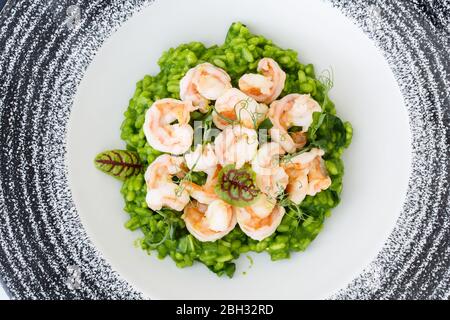 Risotto con basilico e gamberi decorato con microgreens in un piatto. Foto Stock