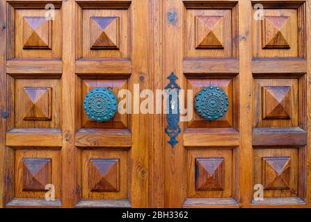 Porta in legno molto elegante e decorativa e pomelli ornamentali in bronzo. Foto Stock