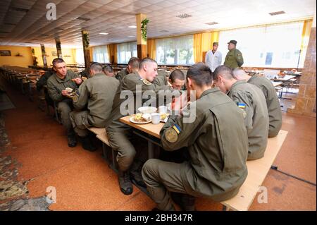 In corrispondenza di un pasticcio hall: soldati seduti al set-tabelle e mangiare. Novo-Petrivtsi base militare, Ucraina. Novembre 12, 2018 Foto Stock