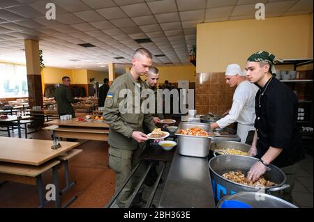 In una sala di mucca: I soldati si trovano davanti ad un bar di servizio e aspettano che il lavoratore della cucina prepari il pasto per la distribuzione. Base militare Novo-Petrivtsi, Regno Unito Foto Stock