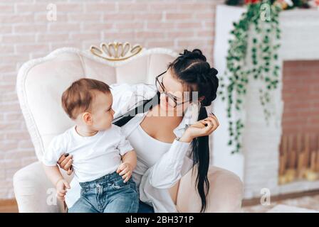 Ragazzino con mamma seduto su una sedia Foto Stock