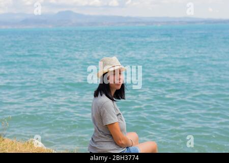 Bella donna lifestyle seduta e rilassante sulla riva del lago contemplando un paesaggio incredibile. Vacanza estiva in famiglia. Rilassatevi. Felicità Foto Stock