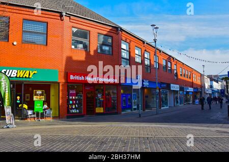 Una vista di negozi moderni lungo Caroline Street, una delle principali aree dello shopping della città di Bridgend. Foto Stock