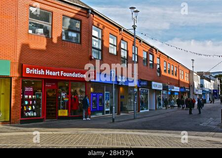 Una vista di negozi moderni lungo Caroline Street, una delle principali aree dello shopping della città di Bridgend. Foto Stock