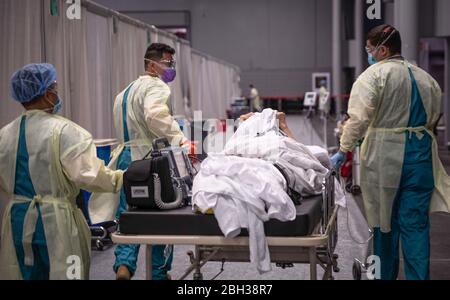 I membri del servizio dell'esercito degli Stati Uniti, schierati da Fort Campbell, Kentucky trasportano un paziente all'unità di cura intensiva alla stazione medica di Javits New York al centro di convenzione di Jacob K. Javits a New York City, in appoggio della risposta del COVID-19 del reparto della difesa. Foto Stock