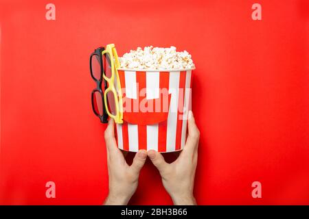 Il tipo tiene il popcorn nelle sue mani su uno sfondo rosso. Inserire il testo. Foto Stock