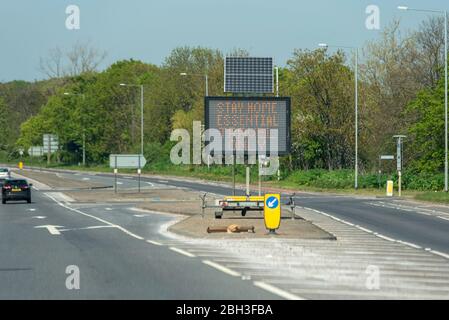 Segnale matrice di traffico sulla A128 vicino all'ospedale Orsett, Essex che chiede alle persone di rimanere a casa, viaggio essenziale solo, durante la pandemia di Coronavirus COVID-19 Foto Stock