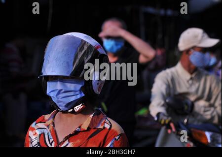 Protezione completa, cambogiani che indossano maschere / rivestimenti protettivi per il viso, alcuni sulle moto, shopping al mercato di Kandal durante la pandemia coronavirus. Phnom Penh, Cambogia. © Kraig Lieb Foto Stock