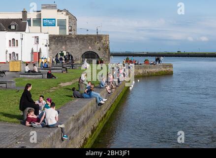 GALWAY, IRLANDA - 21 GIUGNO 2017: Persone che socializzano e godono la vista da Arco Spagnolo lungo la riva del fiume Corrib nella città di Galway. Foto Stock