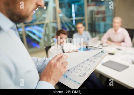 Primo piano di un uomo d'affari che tiene il rapporto nelle sue mani ed esaminandolo prima della presentazione di affari all'ufficio Foto Stock
