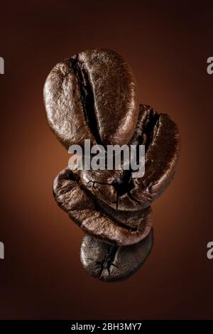 concetto di chicchi di caffè cadenti, primo piano di chicchi di caffè appena tostati che volano su sfondo scuro Foto Stock