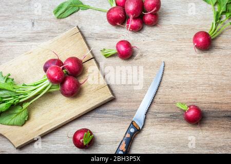 Fresco rosso organico ravanelli con foglie verdi su sfondo di legno. Vista dall'alto con spazio per le copie. Concetto di nutrizione sana. Foto Stock