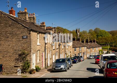 Regno Unito, Inghilterra, Cheshire, Bollington, Lord Street, case su ripida collina con ridondante San Giovanni Battista Chiesa in distanza Foto Stock