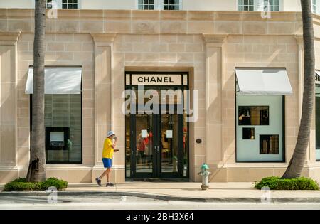 Palm Beach, Florida, Stati Uniti. 23 aprile 2020. Un uomo indossa una maschera mentre cammina davanti al negozio Chanel su Worth Avenue. Solo le imprese essenziali sono state autorizzate a rimanere aperte durante la pandemia di coronavirus. Credit: Gregg Lovett/ZUMA Wire/Alamy Live News Foto Stock