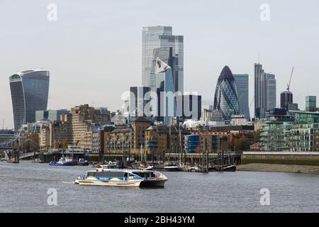 Il Clipper del Tamigi sul Tamigi con i grattacieli della città sullo sfondo, Londra Inghilterra Regno Unito Foto Stock