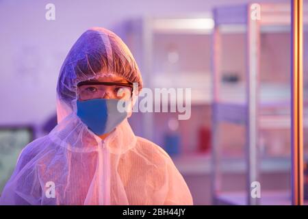 Ritratto dell'infermiere in maschera di protezione e occhiali che guardano la macchina fotografica mentre si trova in ufficio Foto Stock