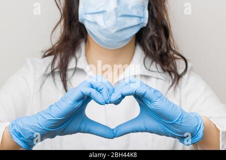 Stop SARSCoV, virus 2020, virus cinese COVID-19. Le donne mano in guanti blu medico mostrano segno di cuore. Concetto di protezione contro l'HIV. Dottore in Foto Stock