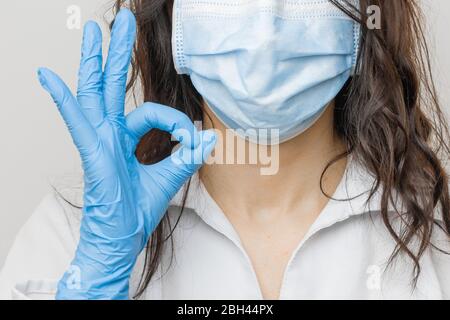 Stop SARSCoV, virus 2020, virus cinese COVID-19. Le donne mano in guanti blu medico mostrano segno OK. Concetto di protezione contro l'HIV. Medico in blu Foto Stock