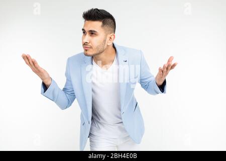 affascinante uomo in una giacca blu classico pensa di una soluzione e un problema su uno sfondo bianco con spazio copia. Foto Stock
