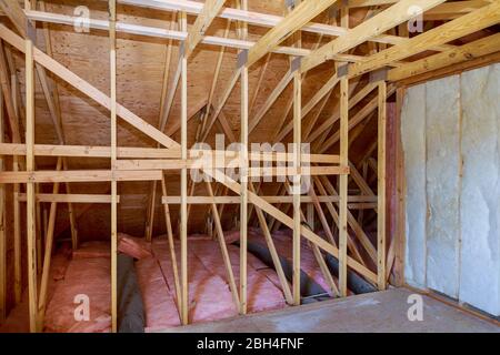 Materiale isolante barriera a freddo in fibra di vetro nella mansarda inclinata di una nuova casa con telaio Foto Stock