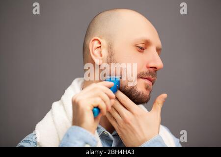 L'uomo taglia la barba con una macchina da scrivere elettrica Foto Stock