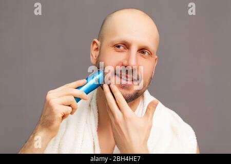 L'uomo taglia la barba con una macchina da scrivere elettrica Foto Stock