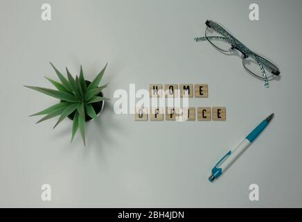 La parola home Office scritto in piastrelle di legno su sfondo bianco. Lavoro di concetto da casa, tecnologia, spazio di lavoro e stile di vita. Foto Stock