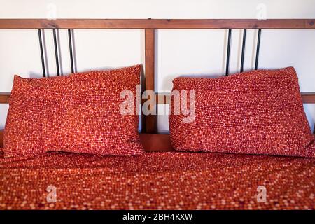 Antico vintage retrò vecchio stile camera da letto con letto rosso arancione modello cuscino in camera con testiera in legno in casa in Europa Foto Stock