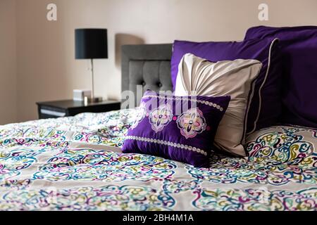 Letto comodo con cuscini colorati e viola coperta in camera da letto Foto  stock - Alamy