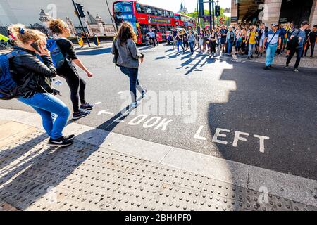 Londra, UK - 21 giugno 2018: Persone che attraversano la passeggiata pedonale a piedi al semaforo da Victoria Embankment Street Road e guardare il segnale a sinistra Foto Stock