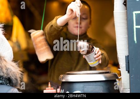 Varsavia, Polonia - 25 dicembre 2019: Lavoratrice donna che versa con ladle muled caldo gluhwein vino in tazza al mercato della città vecchia piazza stand alimentare Foto Stock