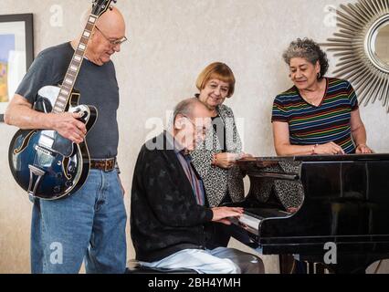 Anziani che guardano l'uomo anziano che suona il piano Foto Stock