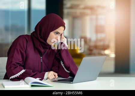 Donna d'affari astica penosa seduta sul posto di lavoro in ufficio Foto Stock