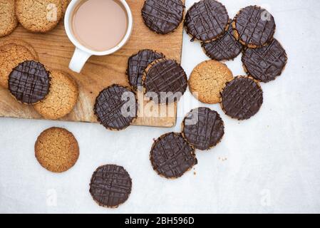 Biscotti fatti in casa con cioccolato fondente e hobbo su un asse di legno con una tazza di tè Foto Stock