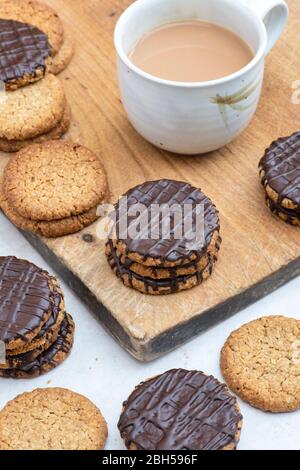 Biscotti fatti in casa con cioccolato fondente e hobbo su un asse di legno con una tazza di tè Foto Stock