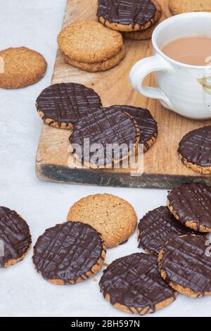 Biscotti fatti in casa con cioccolato fondente e hobbo su un asse di legno con una tazza di tè Foto Stock