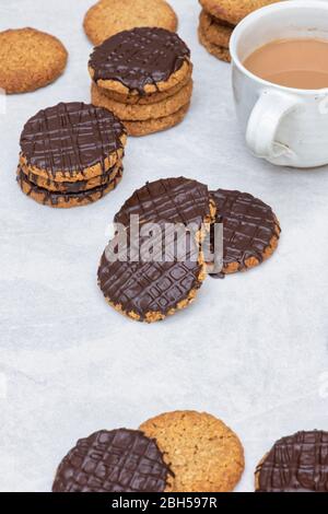 Biscotti fatti in casa con cioccolato fondente e hobbo su un asse di legno con una tazza di tè Foto Stock